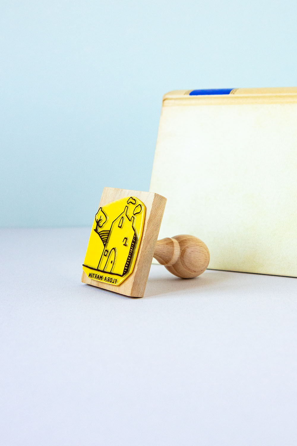 Sello ex-libris con una casa en el campo con humo saliendo de la chimenea y un árbol al lado