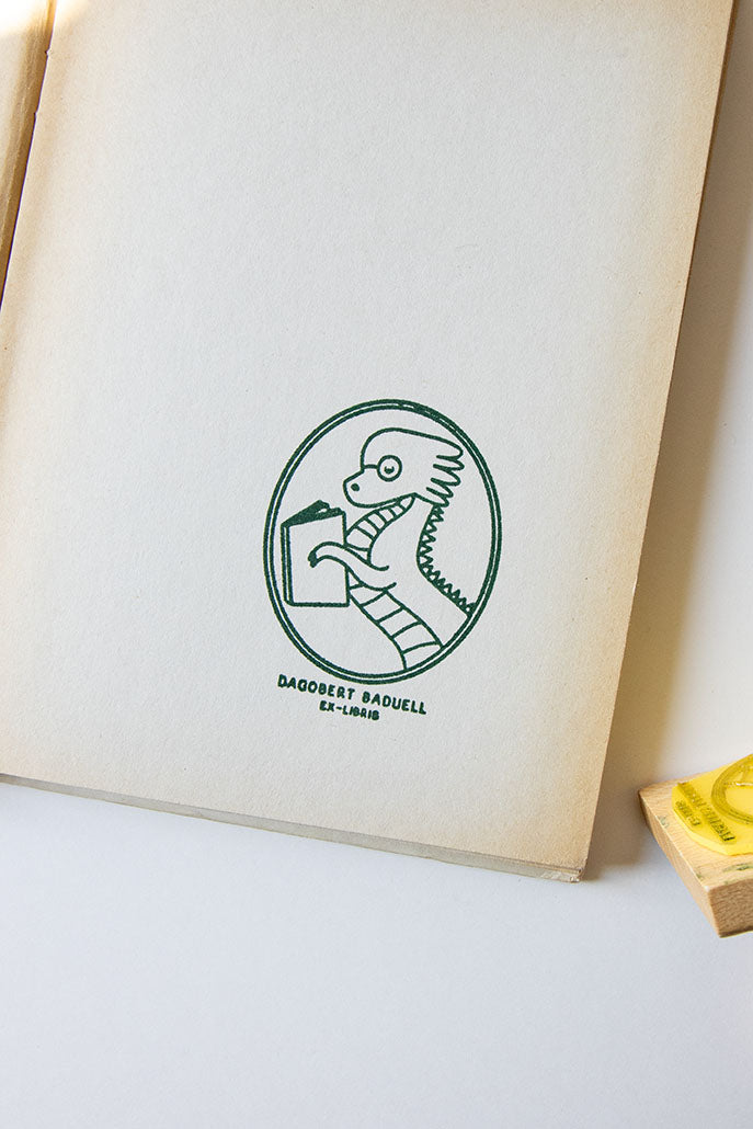 Portadilla de libro estampada con un dragón leyendo y sello