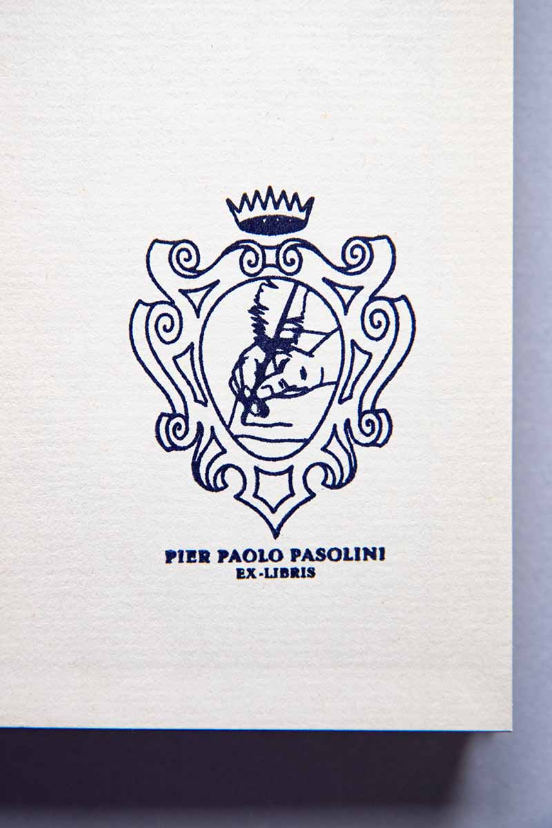 Portadilla de libro estampado con un escudo heráldico con una corona, dentro del escudo se ve una mano escribiendo con una pluma