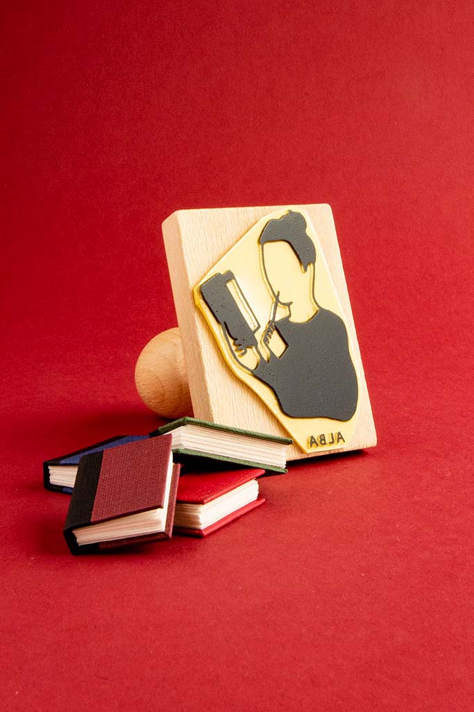 Sello ex-libris de una persona leyendo con un lapiz en la mano