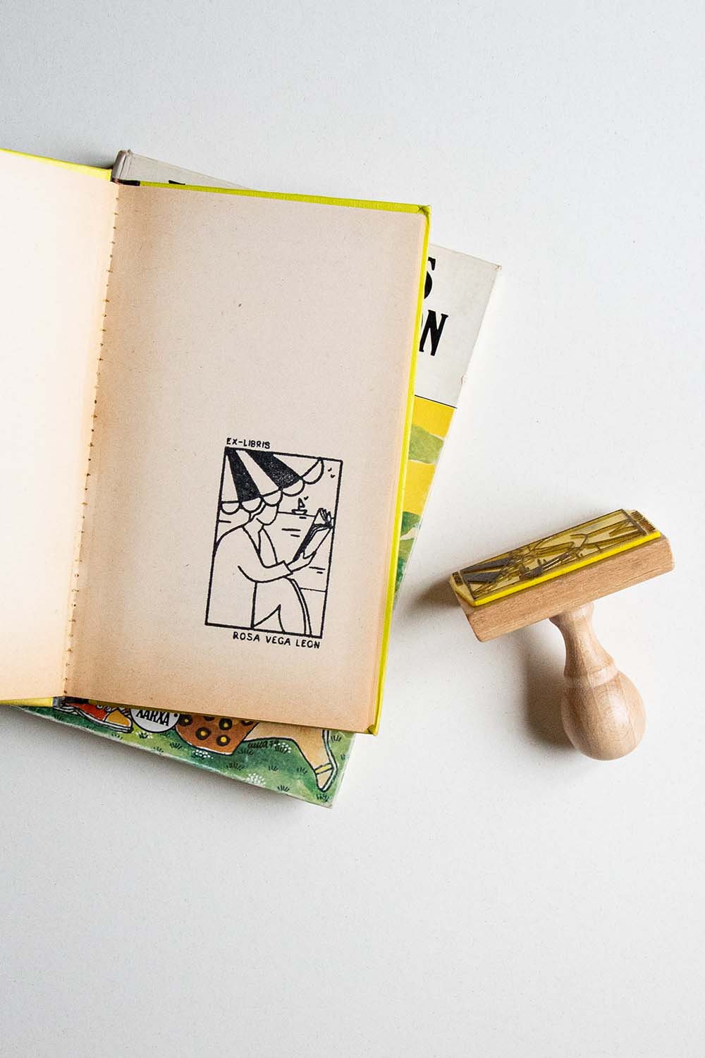 Portadilla de un libro estampada con una persona leyendo bajo la sombrilla en la playa