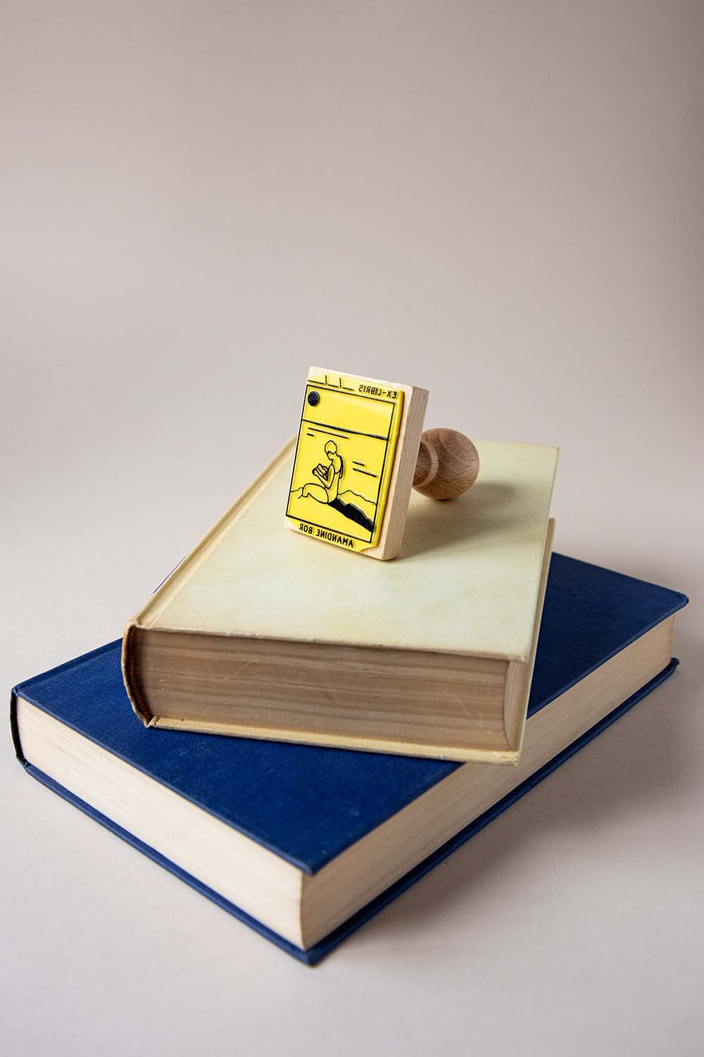 Sello exlibris grabado de una mujer leyendo junto al mar