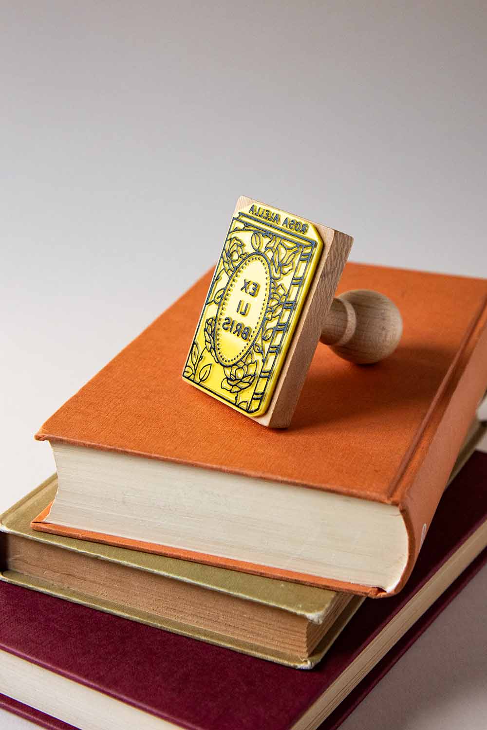 Sello exlibris grabado de un libro con rosas en su portada