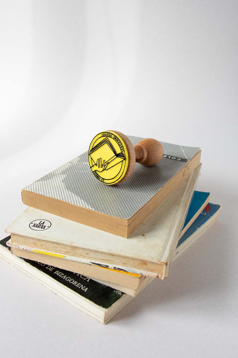 Sello exlibris grabado de una mano sosteniendo un libro