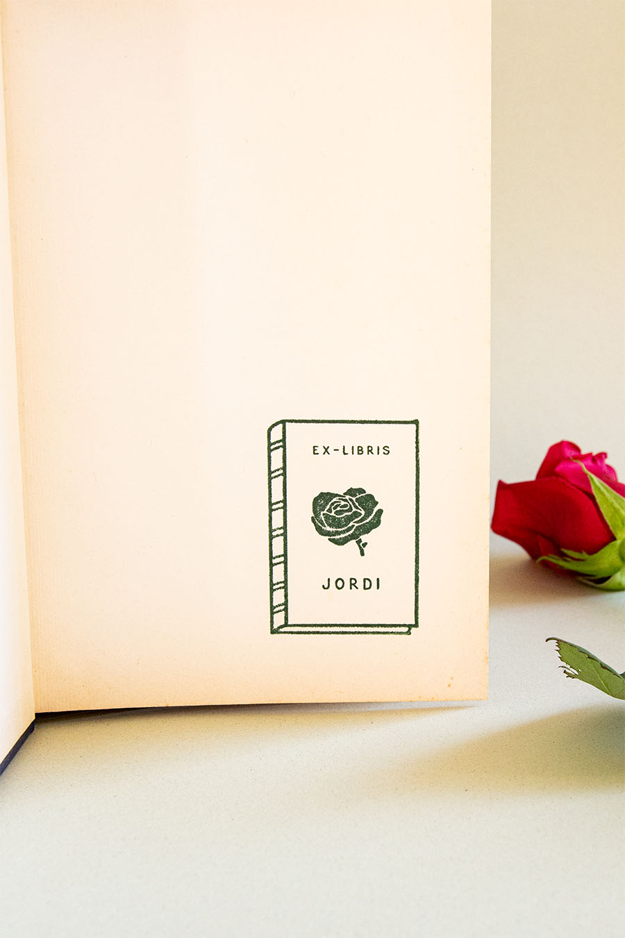 Portadilla de libro estampada con sello exlibris de un libro con una rosa enmedio