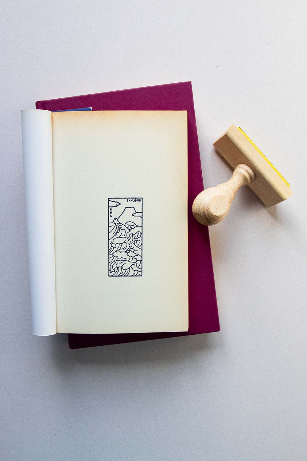 Portadilla de libro estampada con sello exlibris de olas y al fondo el monte Fuji y sello
