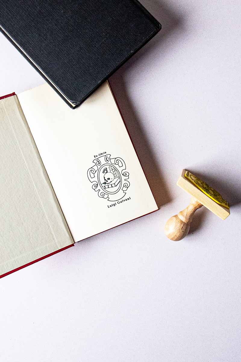Portadilla de libro estampado con un escudo en el que se representa una vanitas con un craneo, libros y una mariposa