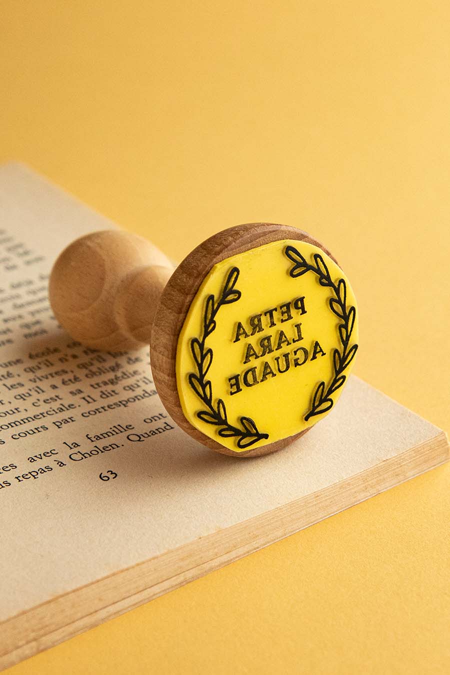 Sello ex-libris con un círculo de hojas de laurel que enmarcan el nombe del propietario