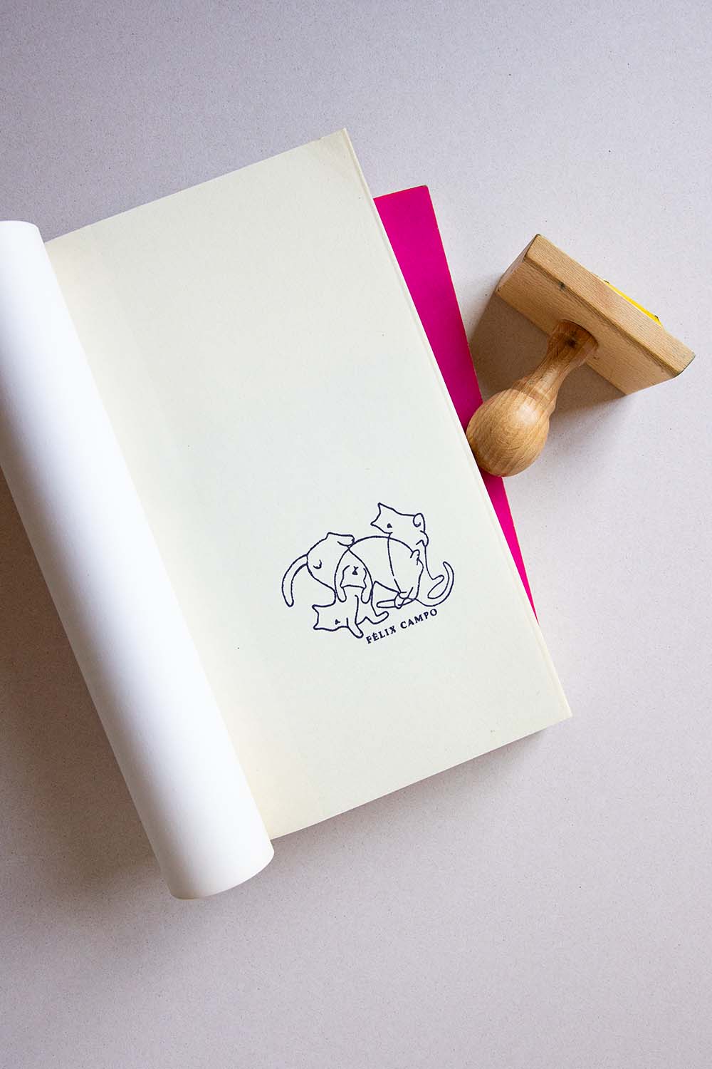 Portadilla de libro estampada con un sello exlibris de tres gatos domésticos jugando y sello