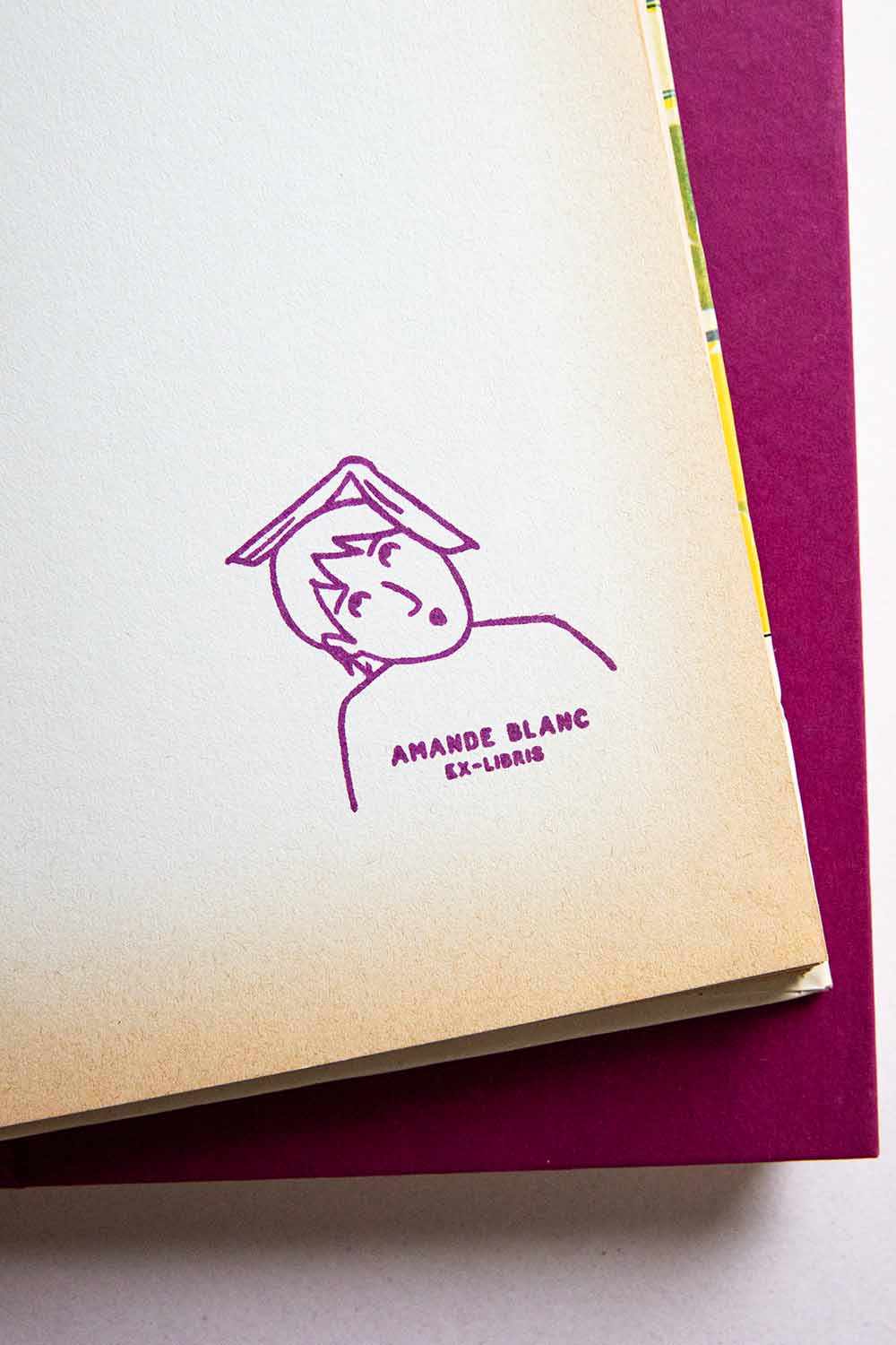 Portadilla de libro estampada con sello exlibris de una lectora sorprendida con un libro abierto en la cabeza