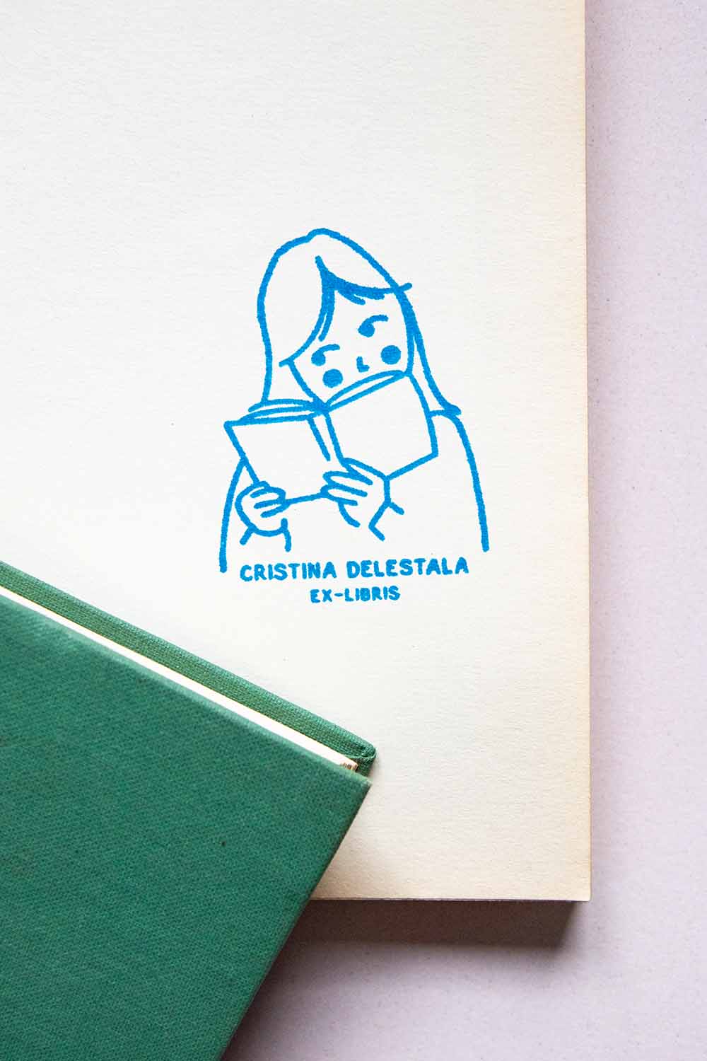 Portadilla de libro estampada con sello exlibris de una niña leyendo
