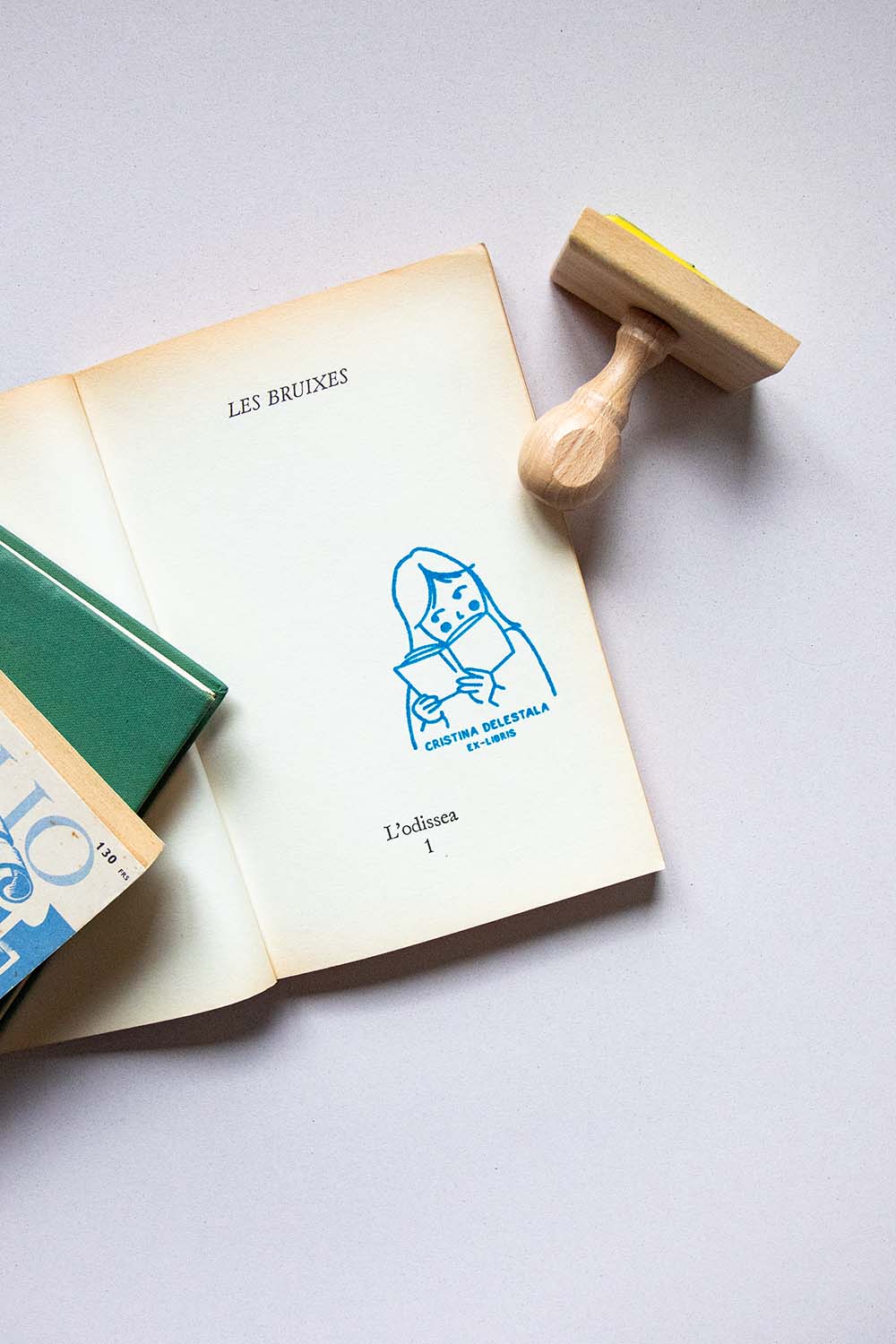 Portadilla de libro estampada con sello exlibris de una niña leyendo y sello