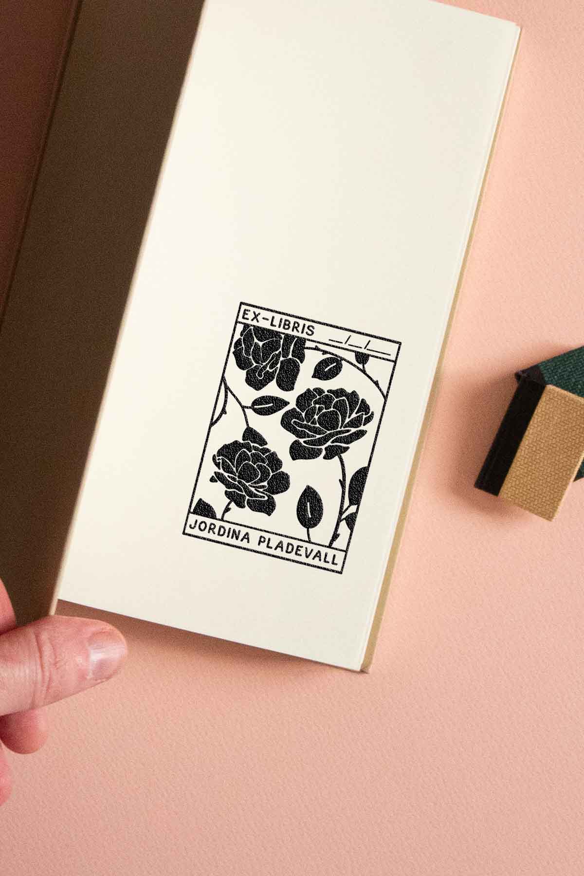 Portadilla de libro estampada con sello exlibris de rosas dentro de un recuadro