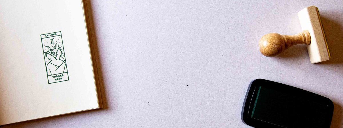 Exlibris personalizado estampado en la guarda de un libro abierto, con el signo del zodiaco Géminis
