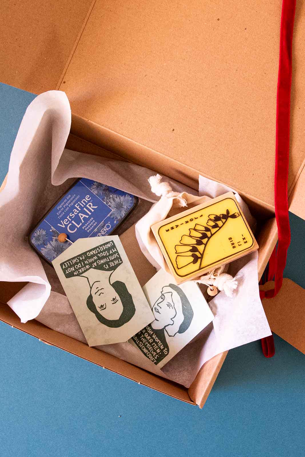 Caja de regalo abierta con sello exlibris, tinta y guirnalda