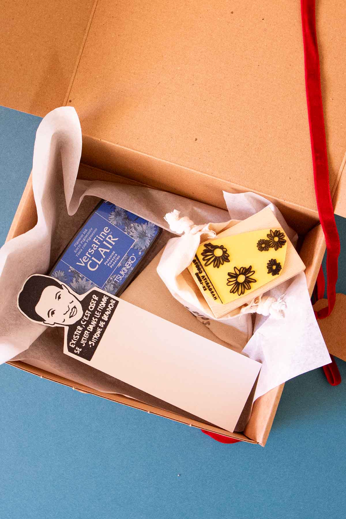 Caja de regalo abierta con sello exlibris, tinta y marcapáginas