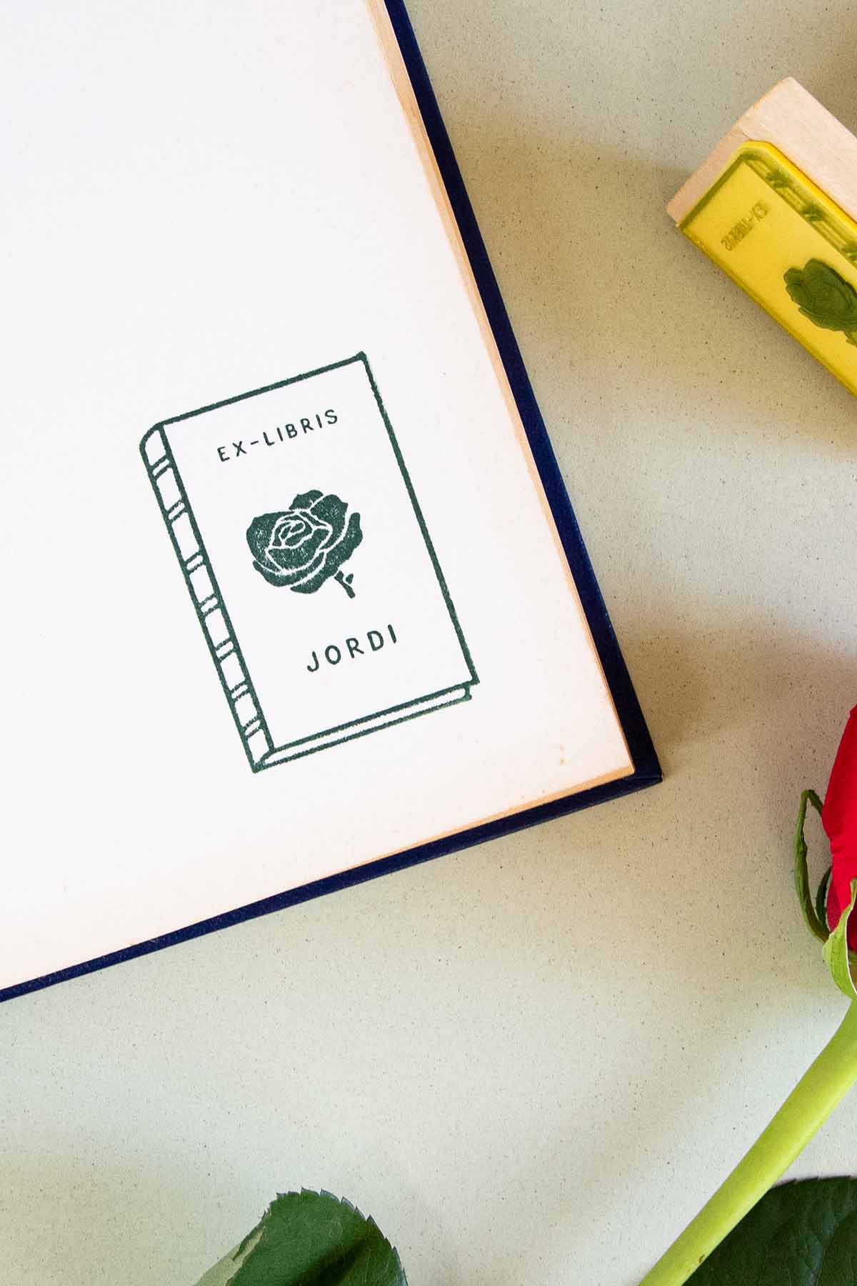 Portadilla de libro estampada con sello exlibris de un libro con una rosa enmedio