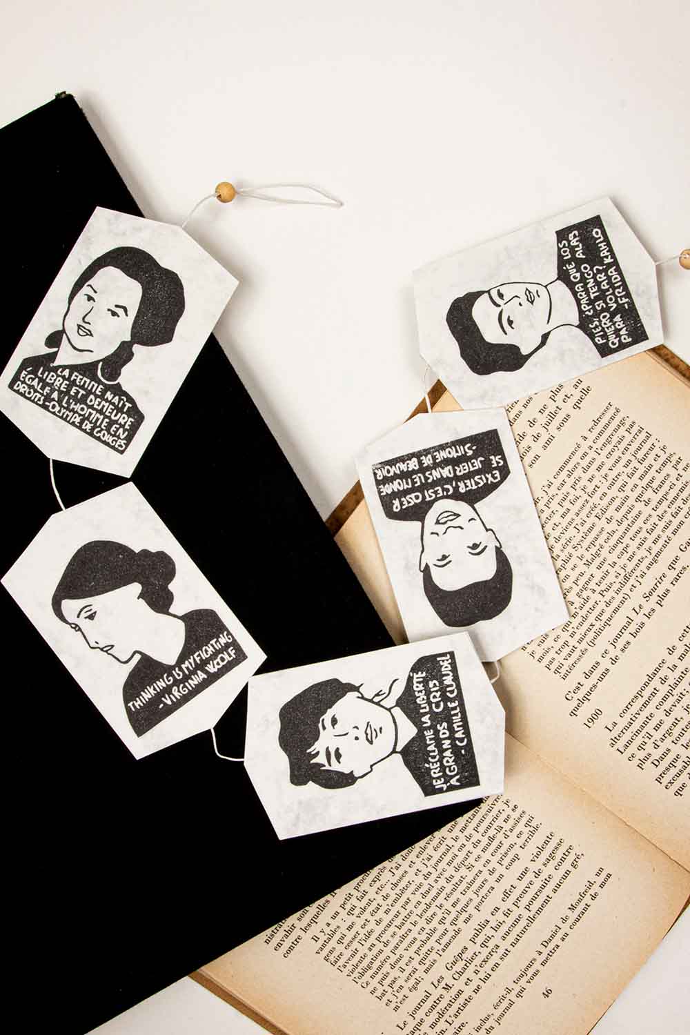 Marcapáginas hechos a mano con retratos de mujeres clásicas de Guirnalda Clásica Mujeres y citas de mujeres famosas, colocados en las páginas de un libro abierto, sobre un fondo blanco de Les Tampons de Roser.