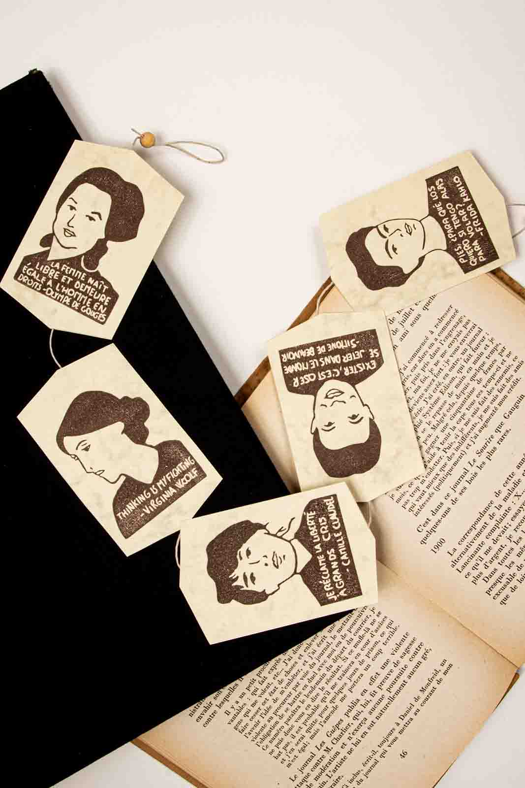 Guirnalda marrón con retratos y citas de Olympe de Gouges, Virginia Woolf, Camille Claudel, Simone de Beauvoir i Frida Kahlo