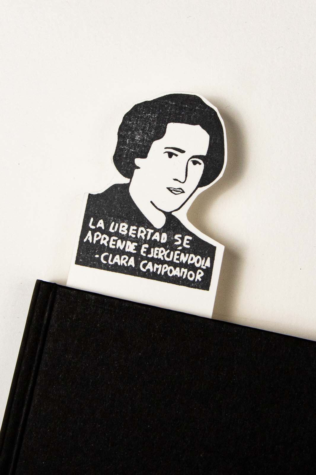 A Marcapáginas Clara Campoamor presenta un retrato en blanco y negro de una mujer con la cita "la libertad se aprende ejerciéndola" de Clara Campoamor, destacada defensora de los derechos de la, por Les Tampons de Roser.